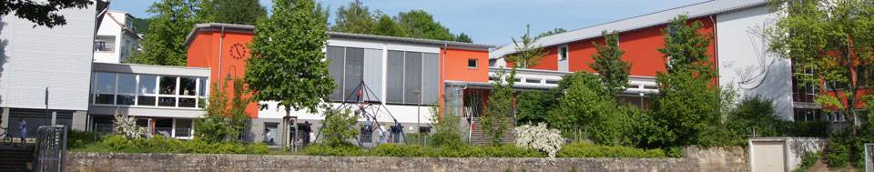 Die Grundschule Grunbach mit ihrer orangefarbenen Fassade, davor der Pausenhof